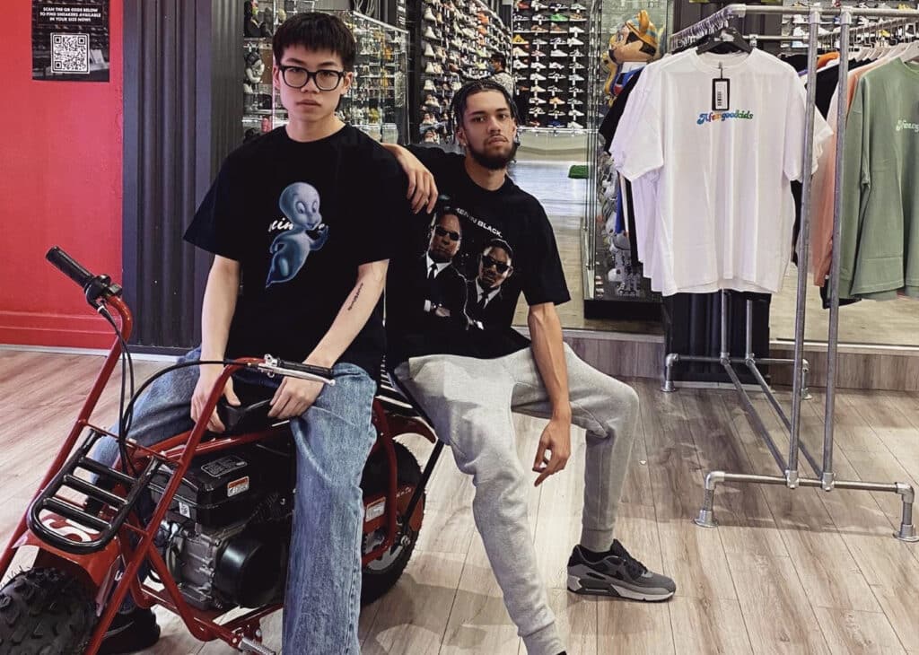 2 male models wearing A Few Good Kids tees with sneakers and streetwear's in background at KICKSTW